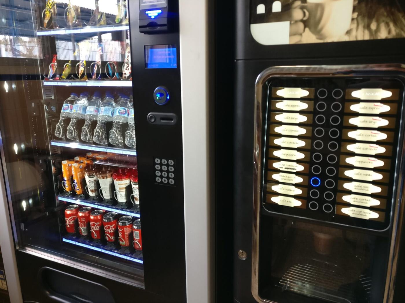 Máquina de snacks y bebidas junto a una cafetera automática en una zona de descanso
